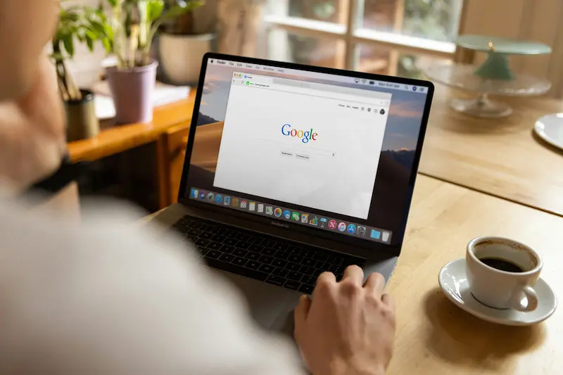 Google search open on a laptop with a coffee cup nearby